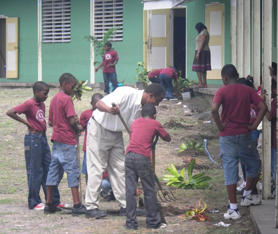 Deputy Principal Mr. Wilroy Gerald demonstrates gardening techniques to students of the Ivor Walters Primary School